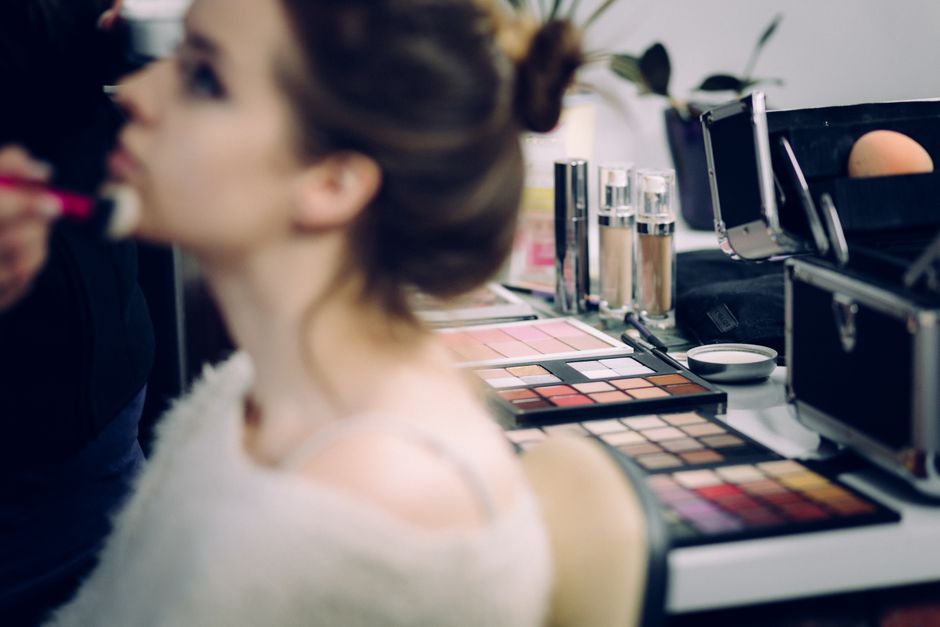 A woman receiving professional makeup in a studio with various cosmetics in focus