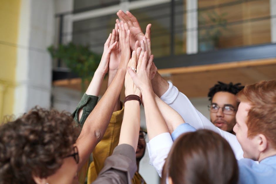A group of diverse professionals celebrating teamwork with a high-five indoors